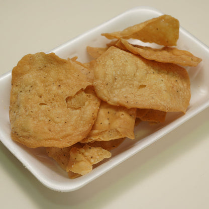 Pile of chaat papri on a white plate with a beige background