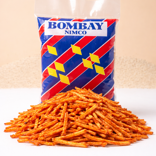 Bag of Bombay Nimco snack with a pile of orange snack sticks on a beige background